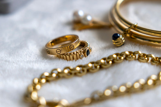Golden jewelry is arranged on a soft white surface.