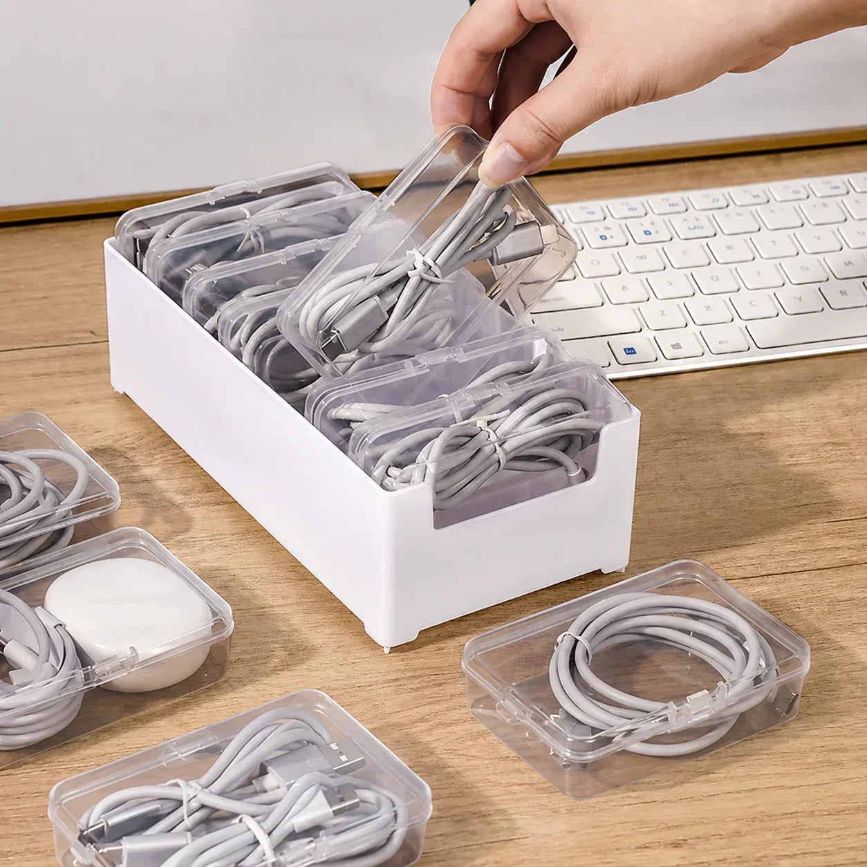 White desktop organizer with clear plastic drawers storing neatly coiled gray charging cables and accessories