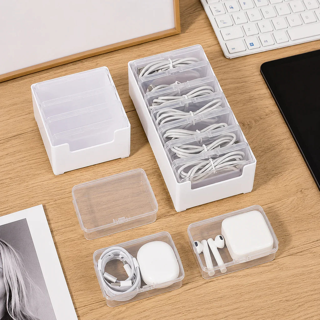 White plastic cable organizer with clear compartments for charging cords and earbuds on wooden desk