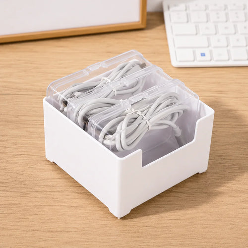 White plastic cable organizer with clear lids holding neatly coiled white charging cords on a desk