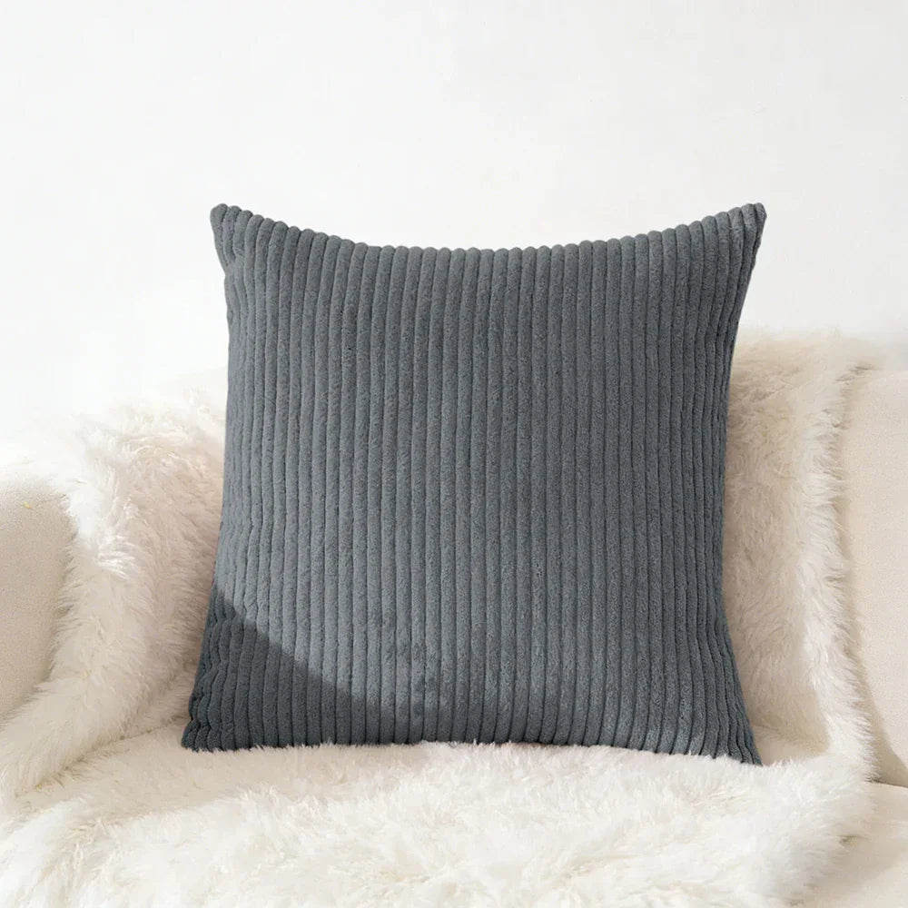 Gray corduroy square pillow on fluffy white chair for cozy home decor