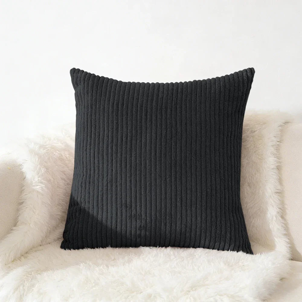 Black corduroy square pillow on fluffy white chair for cozy home décor