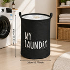 Black fabric laundry hamper with white 'MY LAUNDRY' text, standing in a laundry room next to a washing machine.