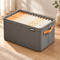 Grey GetVelqo FoldEase fabric storage organizer filled with rolled towels on a wooden floor.