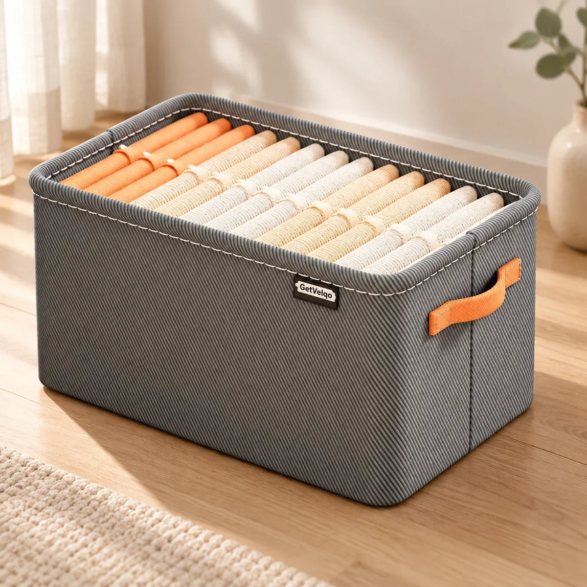 Grey GetVelqo FoldEase fabric storage organizer filled with rolled towels on a wooden floor.
