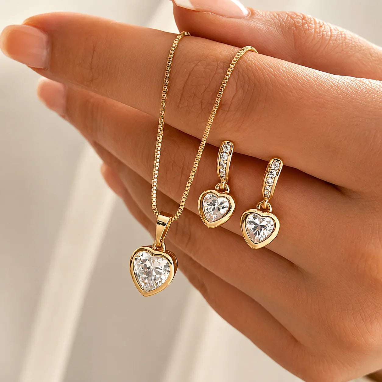 Double Heart gold necklace and earrings set with clear heart-shaped crystals, minimal elegant style