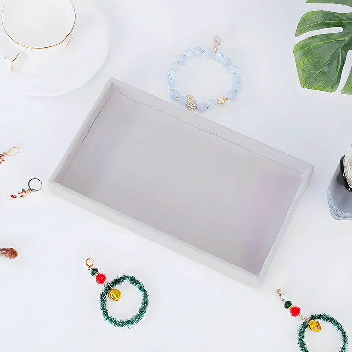 Minimalist blue beaded bracelet with gold accents, festive green wreath earrings, and elegant jewelry tray