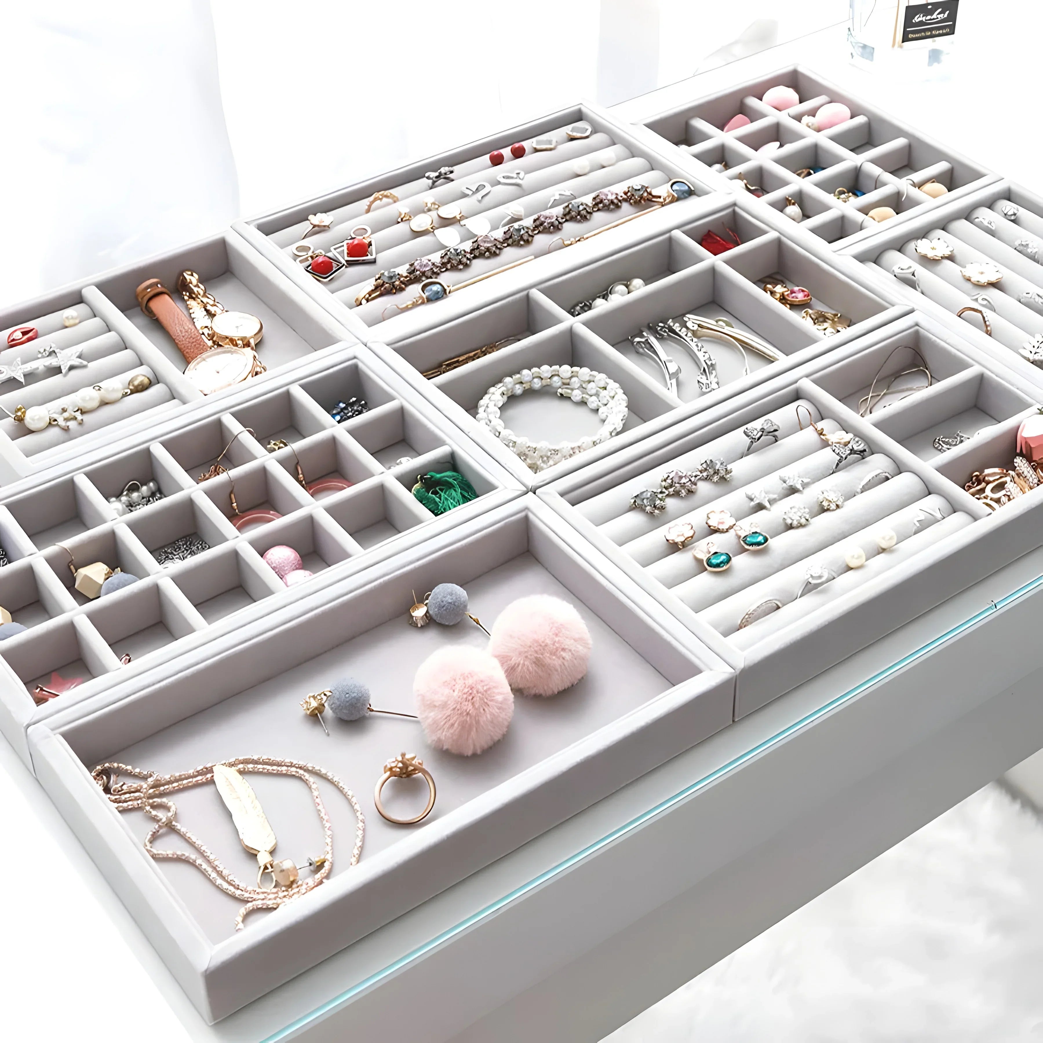 Gray velvet jewelry organizer with rings, earrings, necklaces, and bracelets in gold, silver, and pearl tones