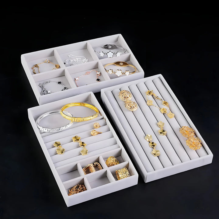 Gold and silver bracelets, earrings, rings in minimalist white display boxes, showcasing elegant, everyday jewelry designs.