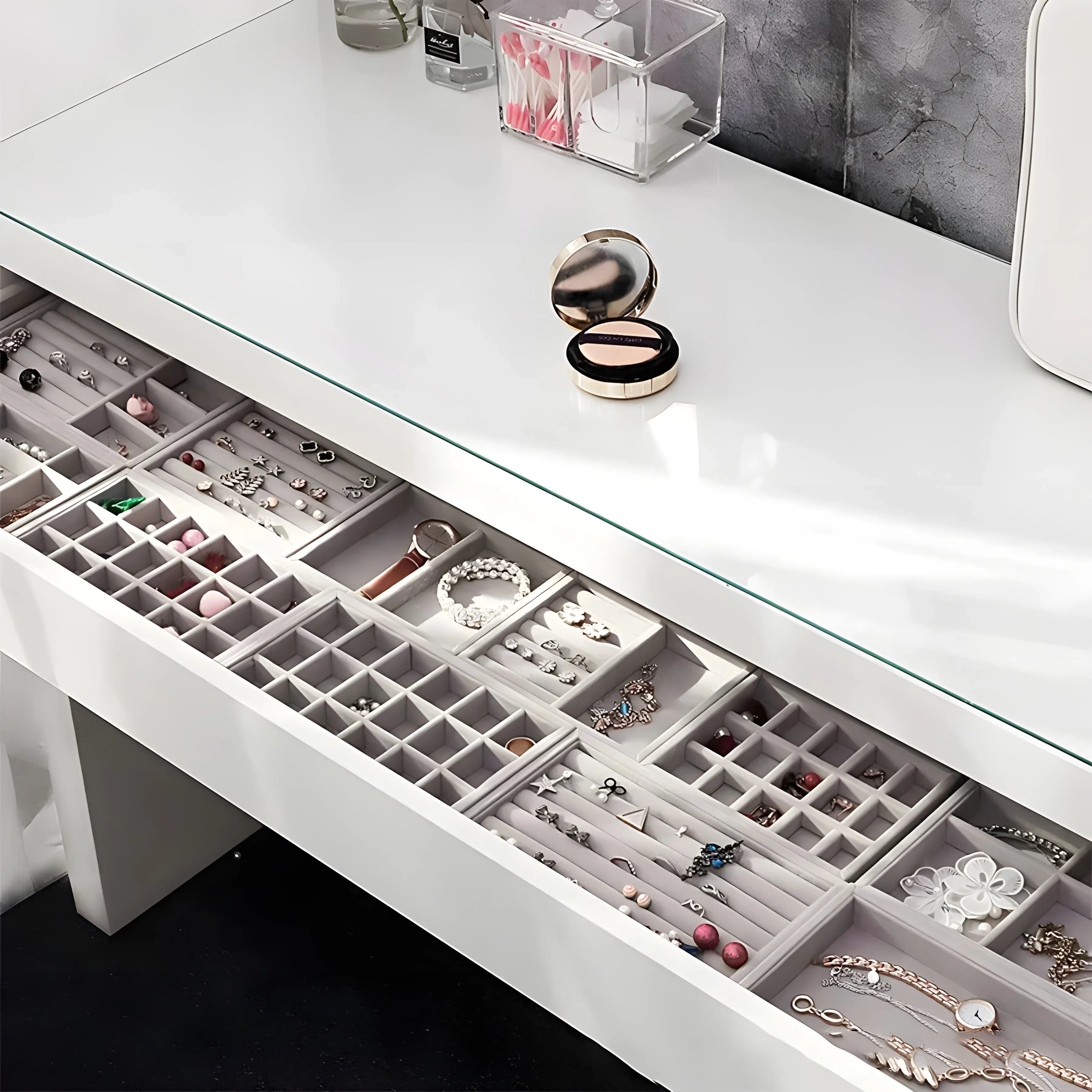 Minimalist jewelry drawer with organized compartments holding rings, earrings, bracelets, and necklaces in silver, gold, and rose gold tones.