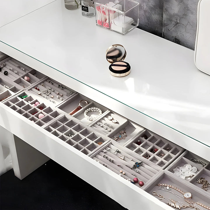 Minimalist jewelry drawer with organized compartments holding rings, earrings, bracelets, and necklaces in silver, gold, and rose gold tones.