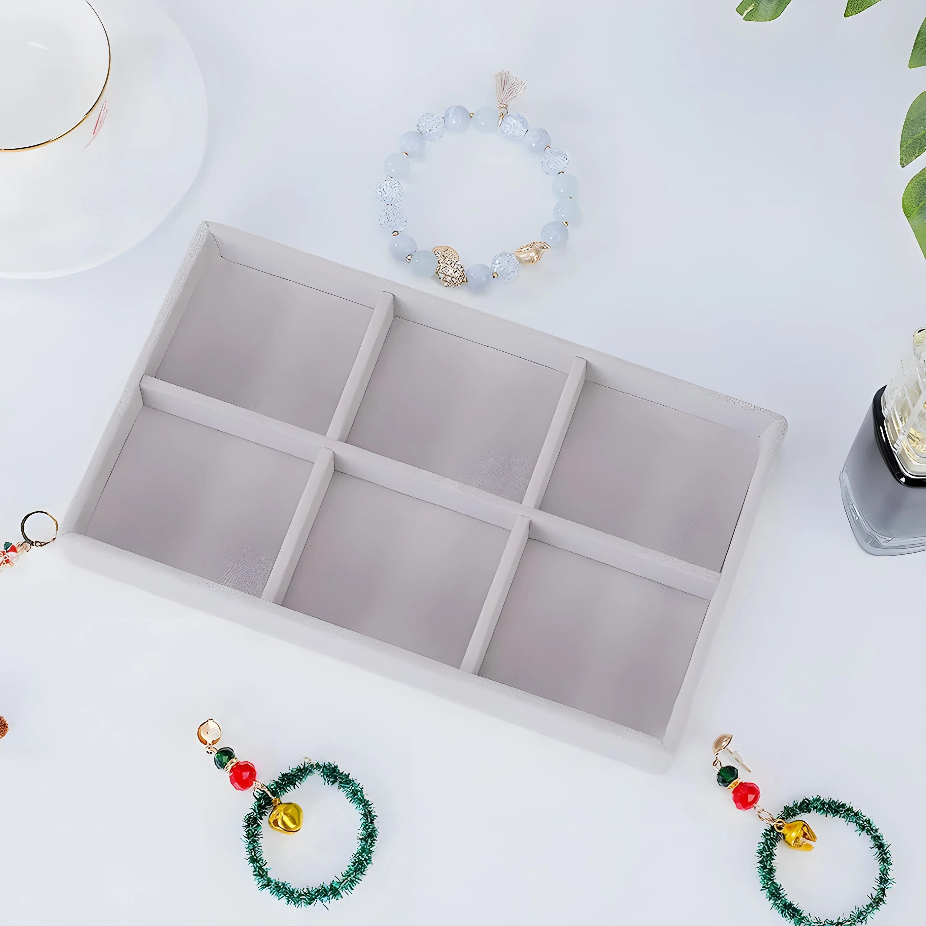 White velvet jewelry tray with six compartments, styled with beaded bracelets and holiday charms for organized storage.