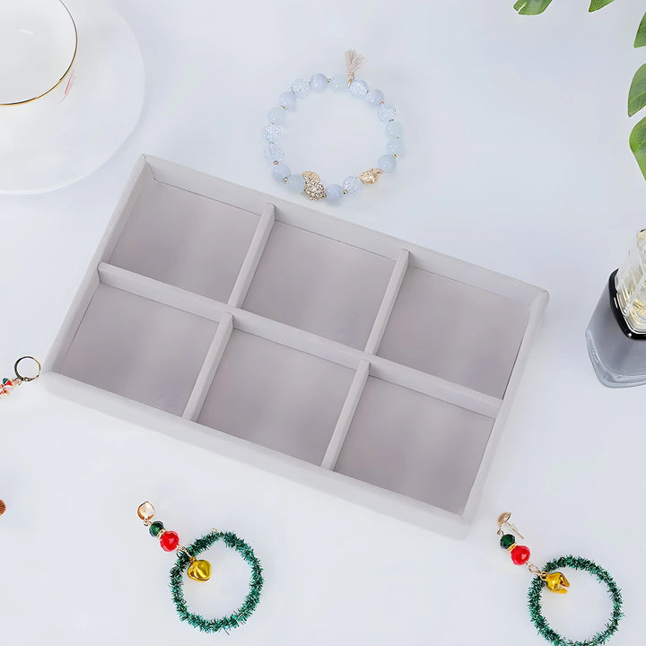 White velvet jewelry tray with six compartments, styled with beaded bracelets and holiday charms for organized storage.