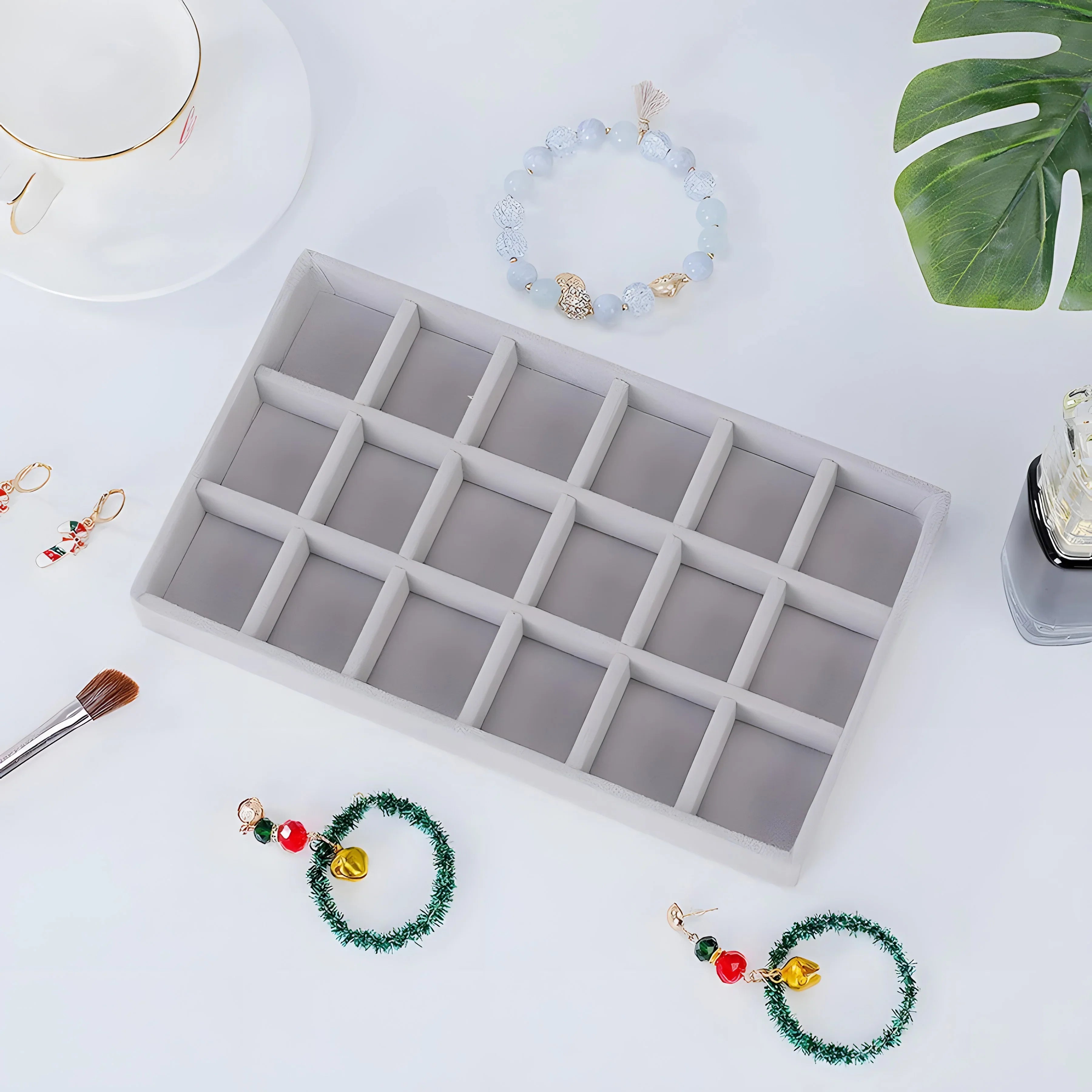 Minimalist gray velvet jewelry tray with compartments, styled with beaded bracelets and festive earrings for organized storage.