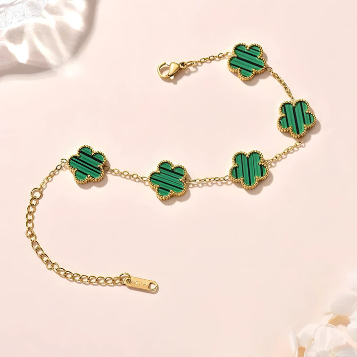 Gold bracelet with green clover charms, striped enamel, minimal style