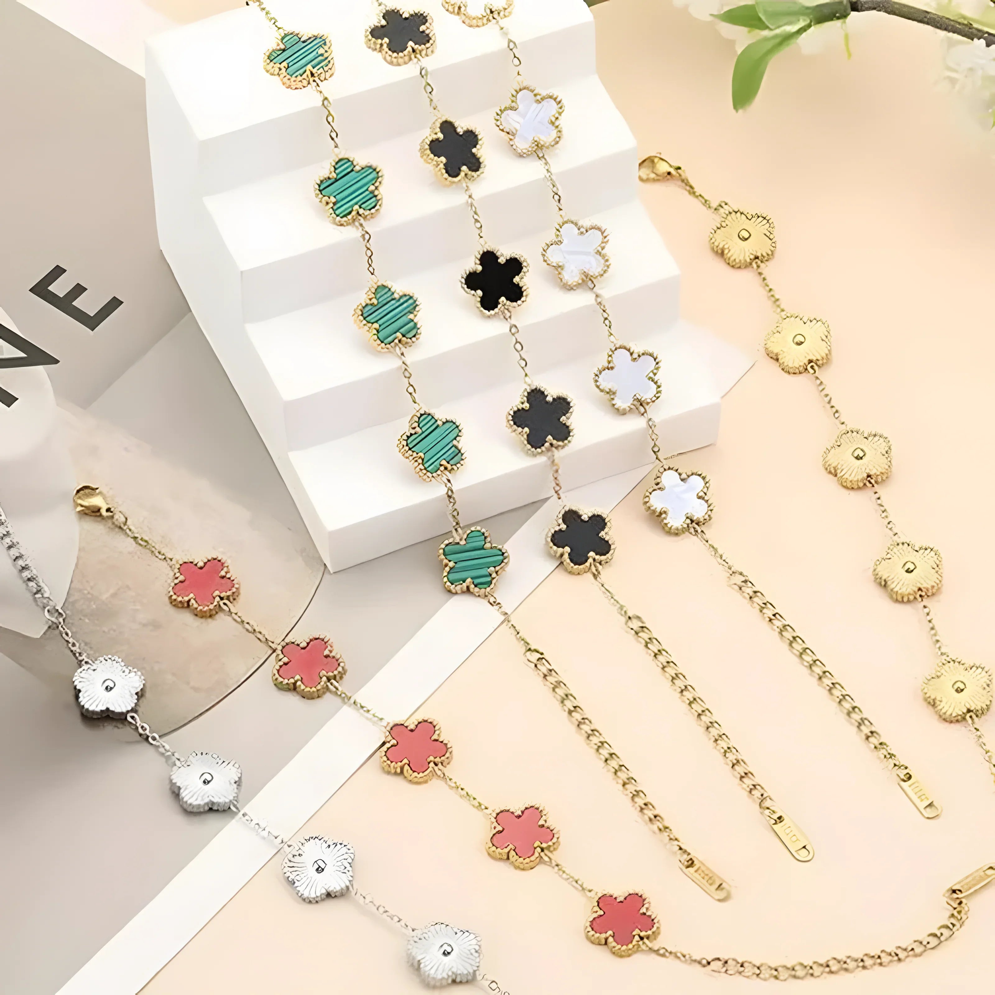 Gold and silver clover charm bracelets in green, black, white, pink, and gold tones, minimalist style