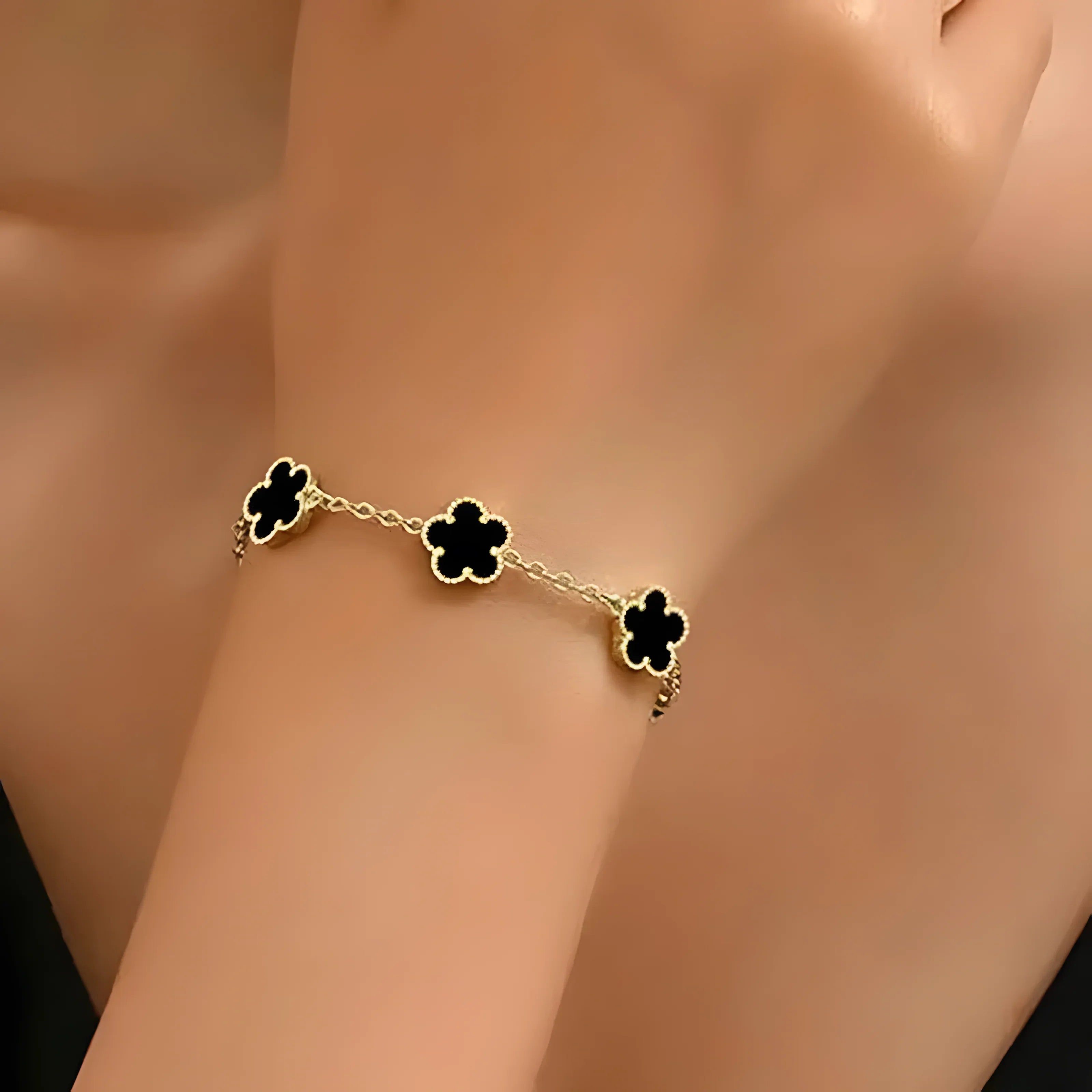 Gold chain bracelet with black clover charms, minimalist style