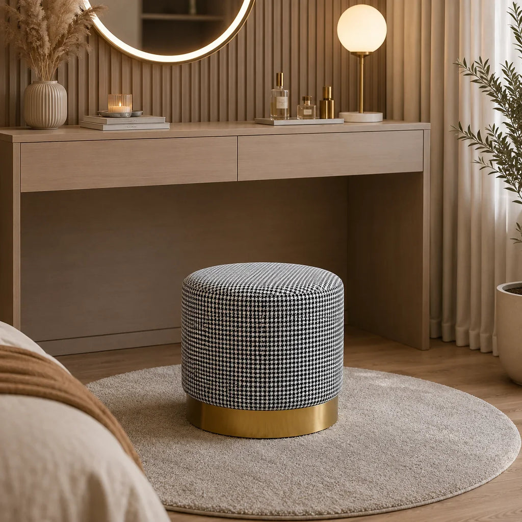 Black and white houndstooth fabric ottoman with gold base, styled in modern bedroom near vanity