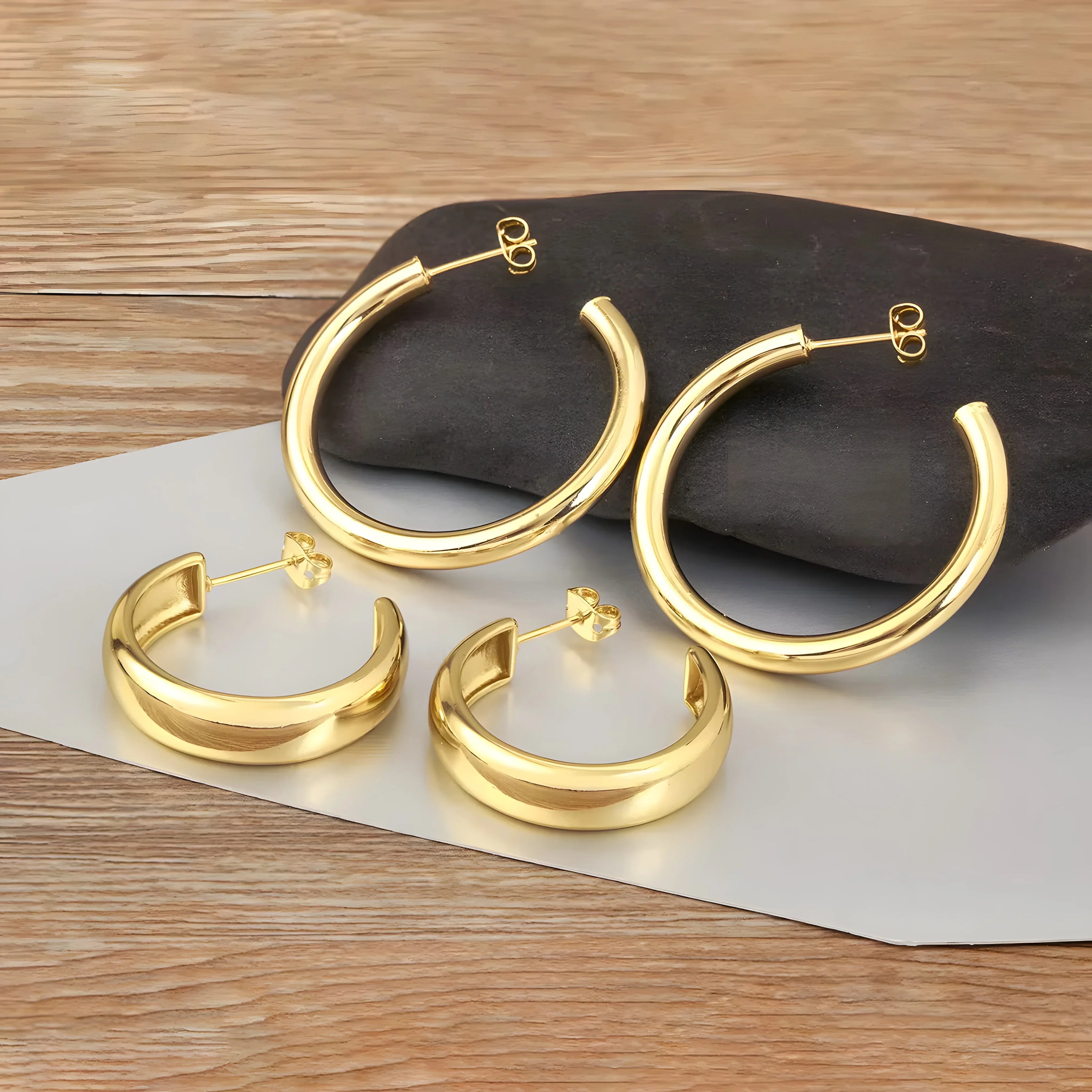 Minimal gold hoop earrings set, polished finish, classic round style, metal jewelry on wood.