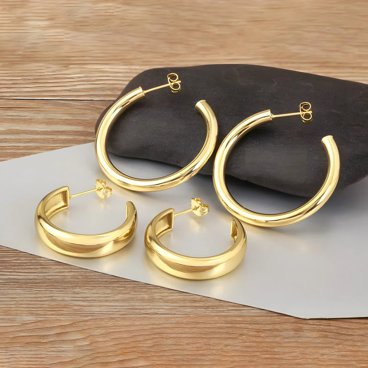 Minimal gold hoop earrings set, polished finish, classic round style, metal jewelry on wood.
