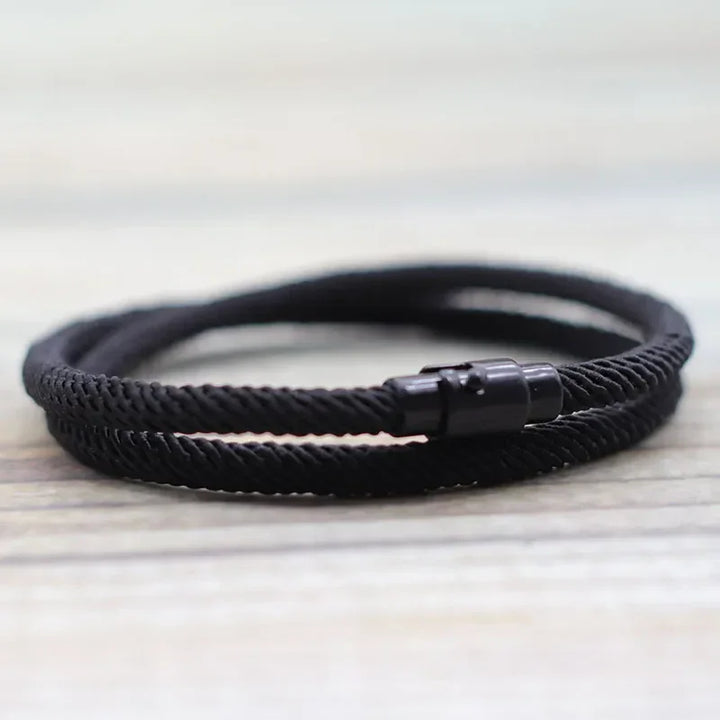 Minimalist rope bracelet, black braided cord with metal clasp, modern jewelry style.