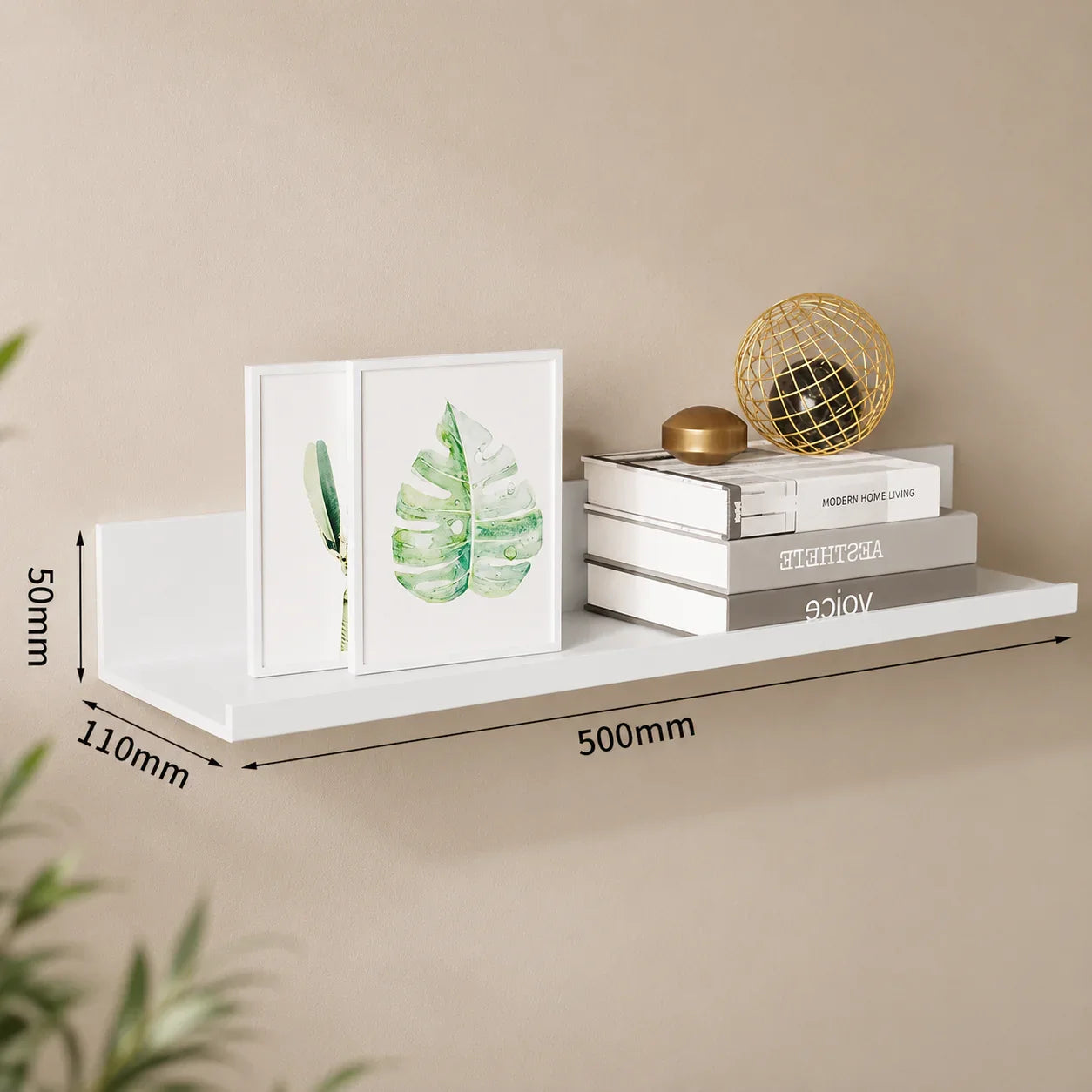 White floating shelf with framed leaf art, books, and gold decor for modern home organization