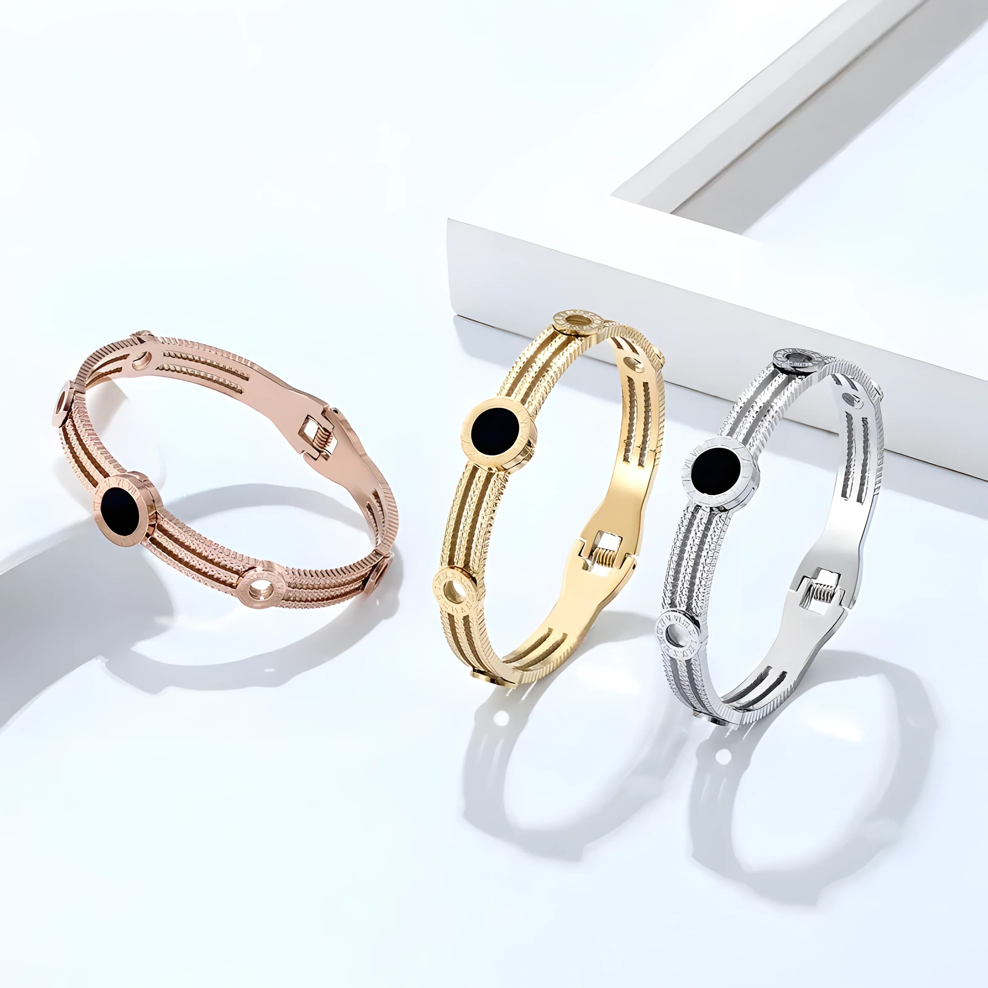 Minimalist bangle bracelets in rose gold, gold, and silver with black stone accents, sleek modern style