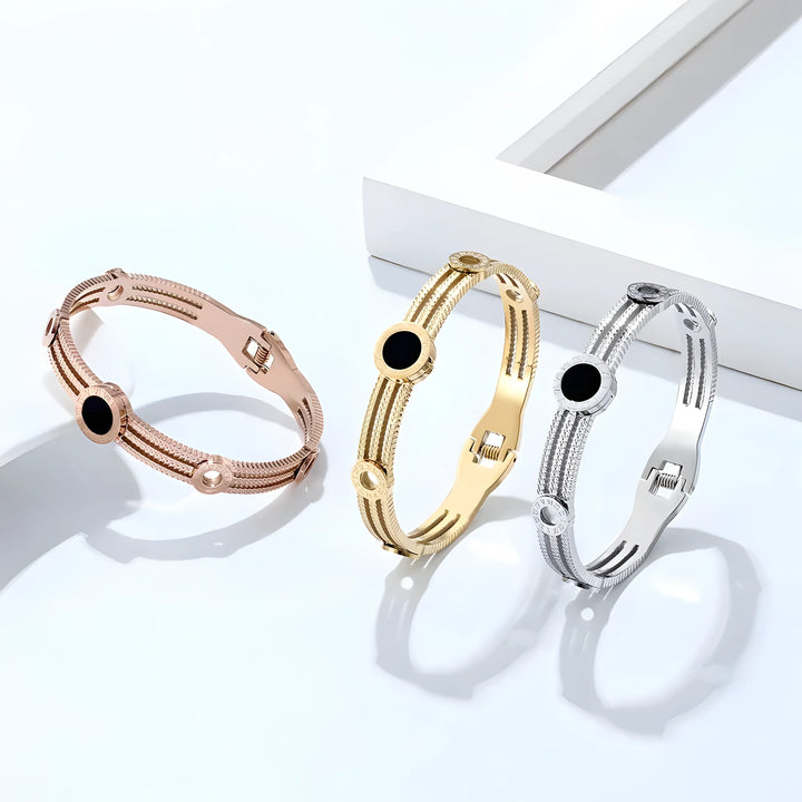 Minimalist bangle bracelets in rose gold, gold, and silver with black stone accents, sleek modern style