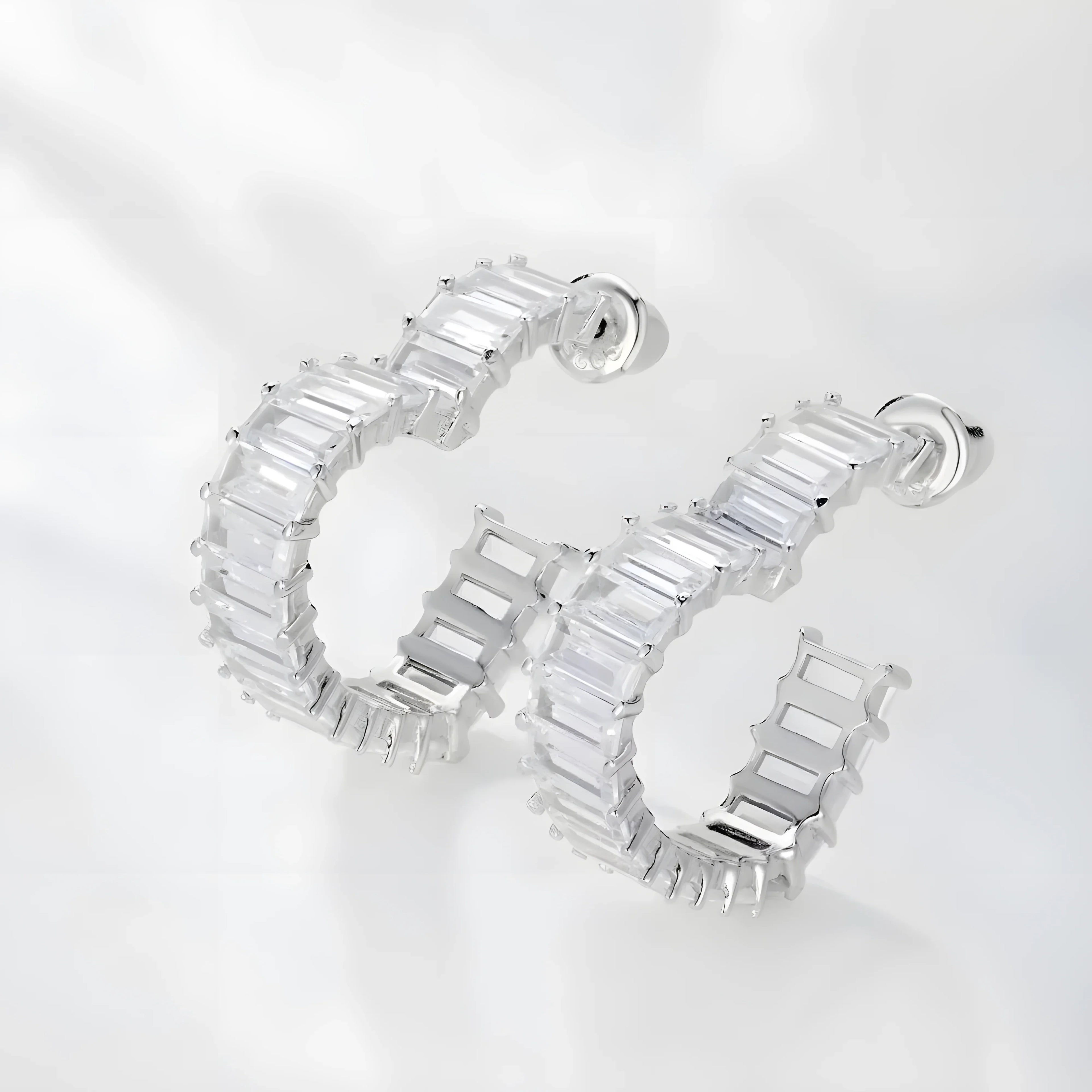 Silver hoop earrings with clear baguette stones, minimal modern design, photographed on white background.