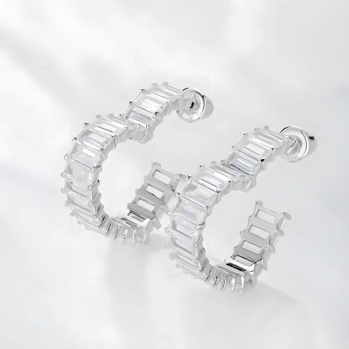 Silver hoop earrings with clear baguette stones, minimal modern design, photographed on white background.
