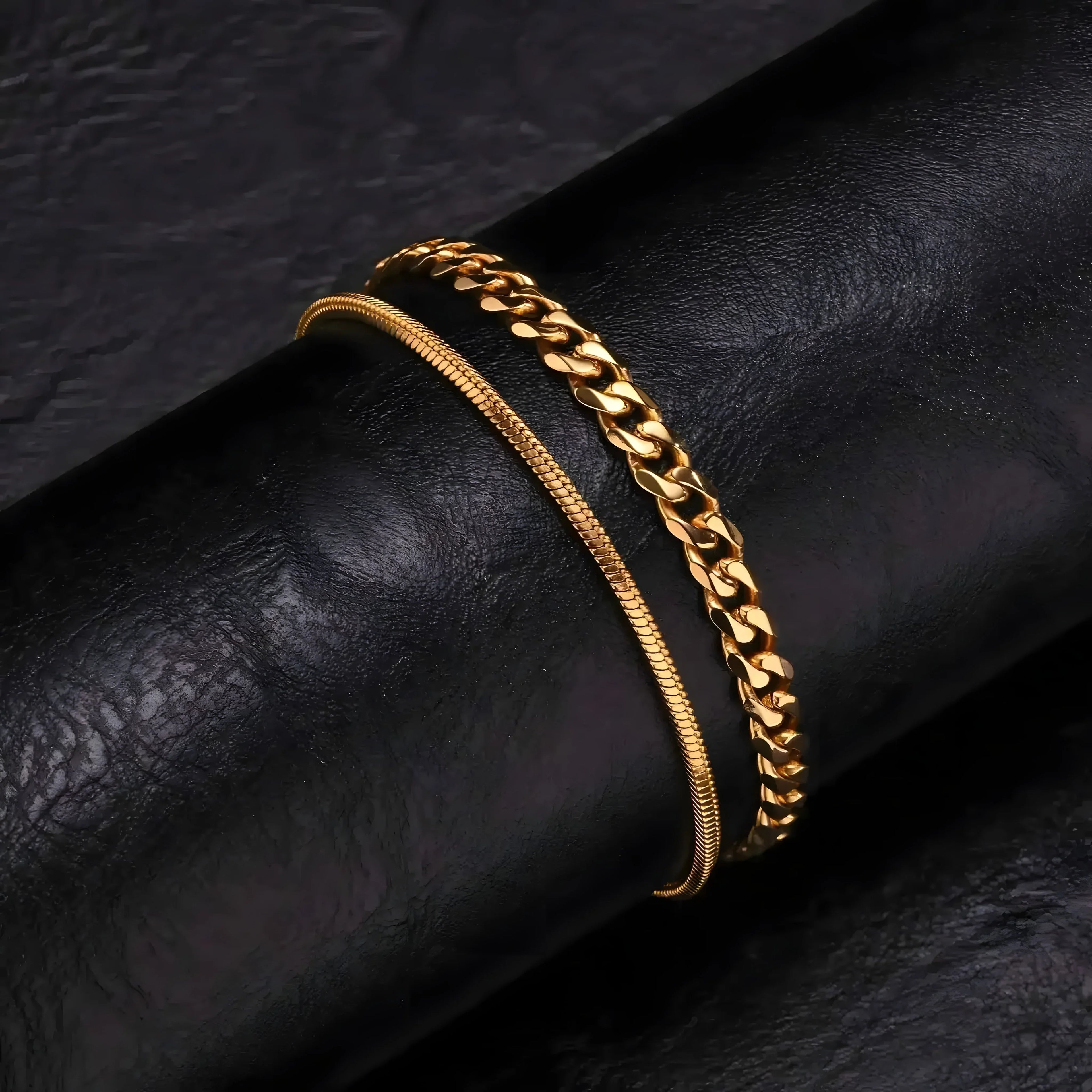 Gold chain bracelets: sleek snake chain and bold curb link, minimalist style on black leather