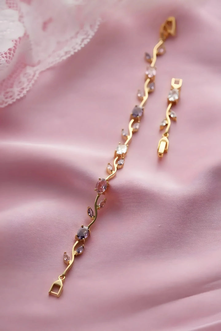 Gold vine-style bracelet with pink and clear gemstones on soft pink fabric, minimalist everyday jewelry