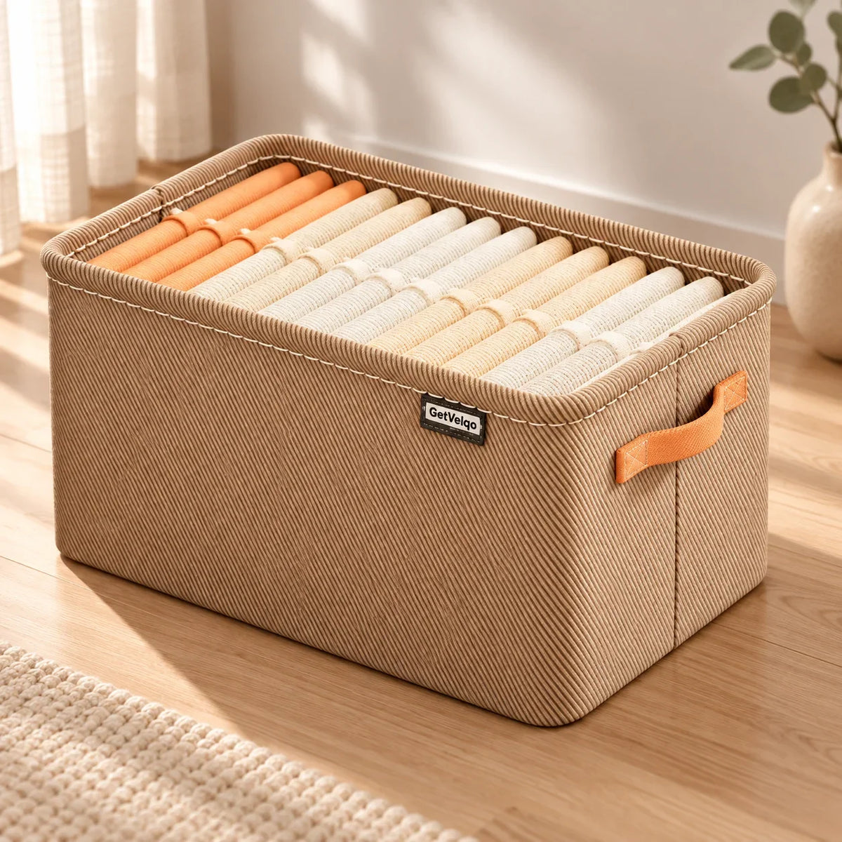Brown fabric GetVelqo storage organizer bin filled with neatly folded orange and white clothing.