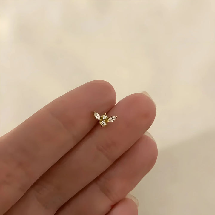 Zircon stud earring in gold, minimalist design with clear stones, shown on fingertip